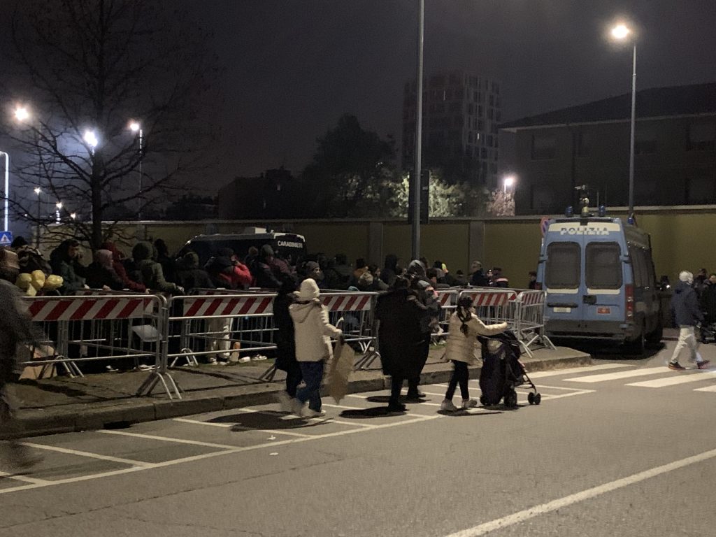 Madri e bambini si incamminano verso l'Ufficio immigrazione, dopo essere stati selezionati dalle forze dell'ordine