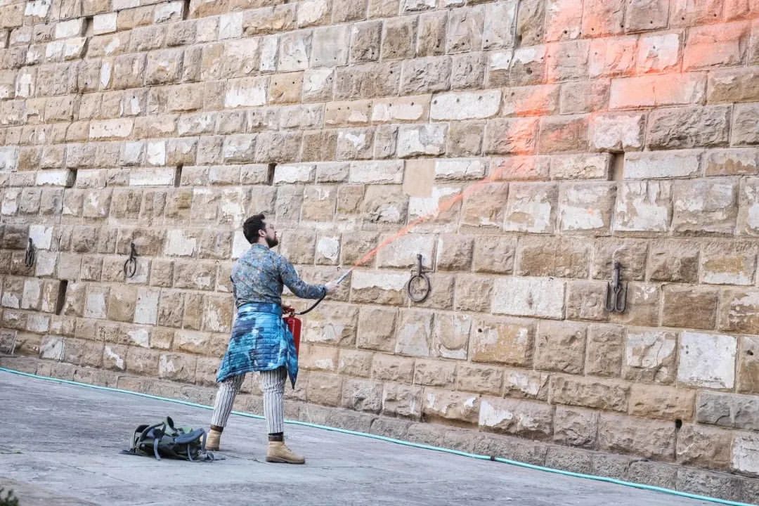 Un attivista di Ultima Generazione spruzza della vernice colorata sulle mura di Palazzo Vecchio, a Firenze
