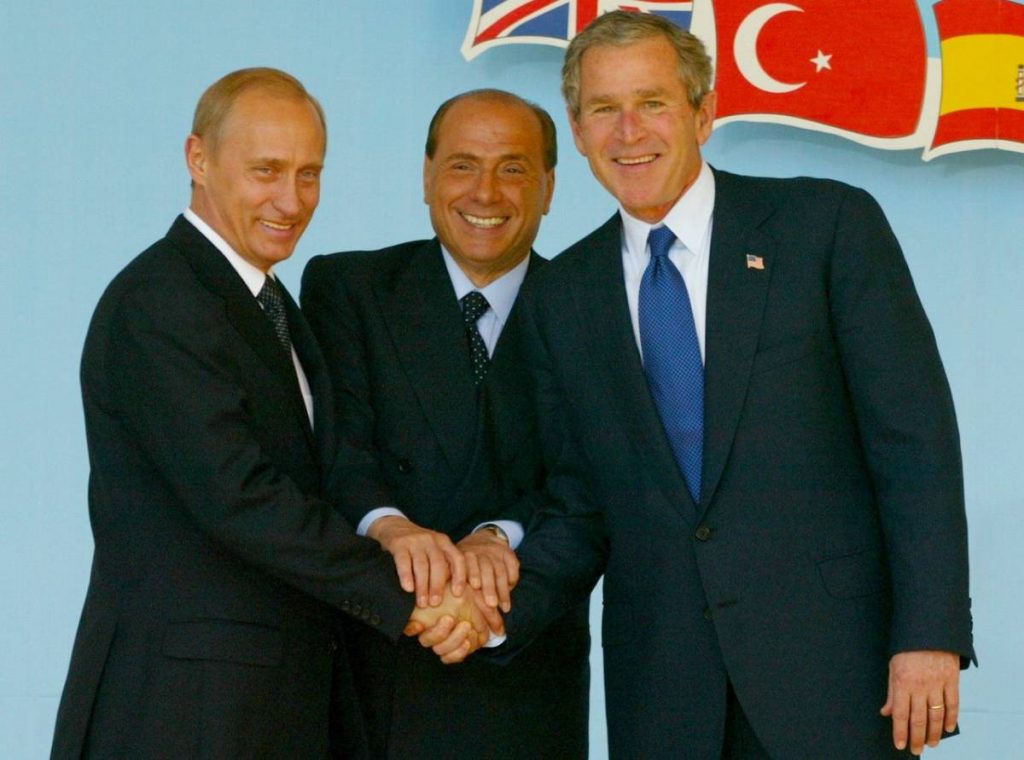 Nel maggio 2002, a Pratica di Mare, l'allora premier Silvio Berlusconi posa le sue mani sopra quelle dei Presidenti di Russia e Stati Uniti, rispettivamente Vladimir Putin e George W. Bush. Con il gesto vuole simboleggiare il suo ruolo di mediazione nella fine della Guerra Fredda