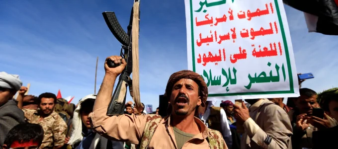 Un miliziano Houthi con le bandiere dello Yemen e del movimento armato ribello (con slogan in arabo).