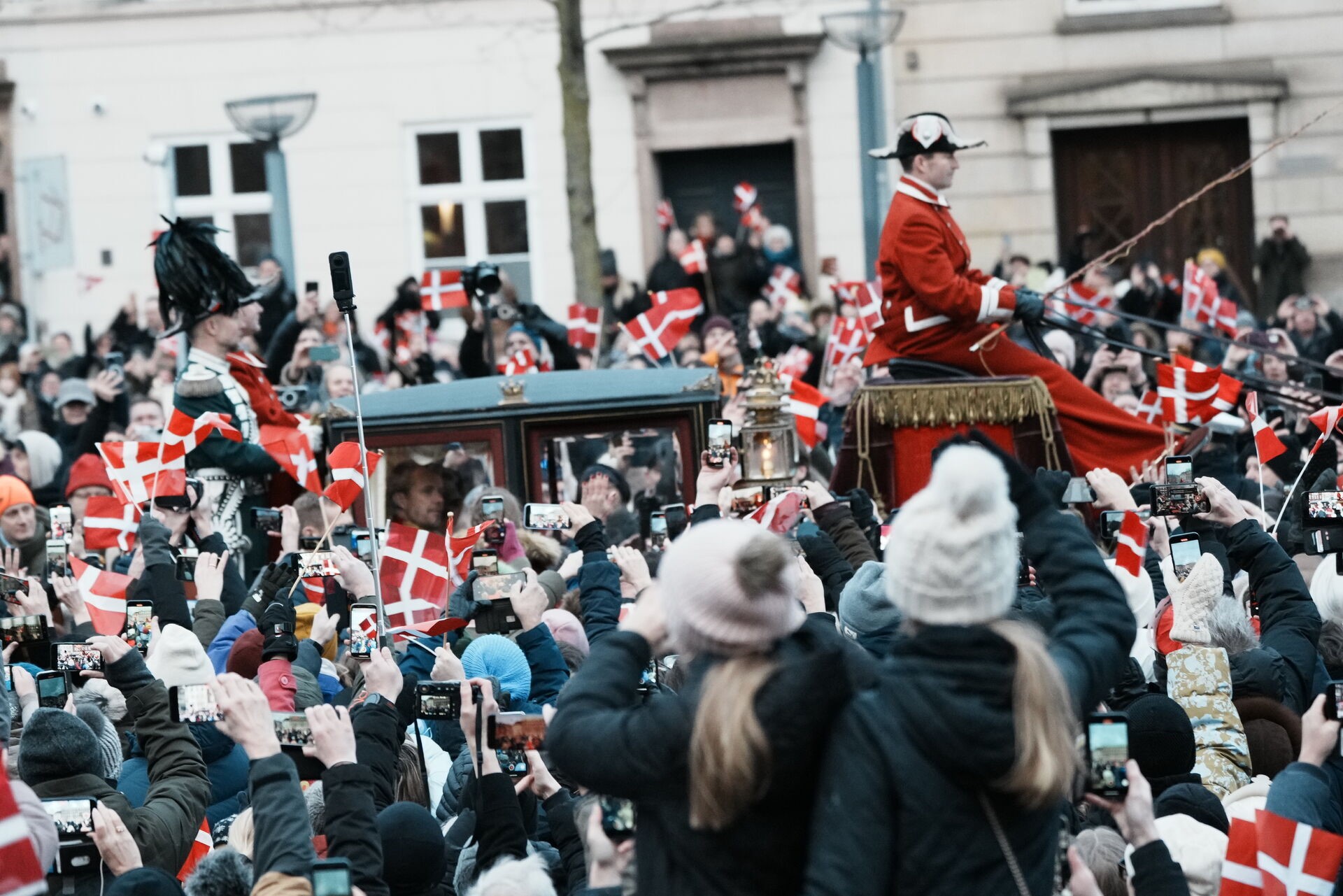 La carrozza che riporta a casa i nuovi re e regina di Danimarca, circondata dalla folla.