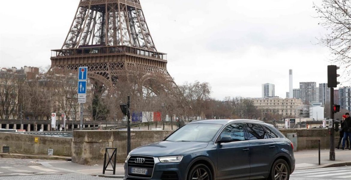 Un Suv percorre una strada di Parigi. Alle spalle la Tour Eiffel